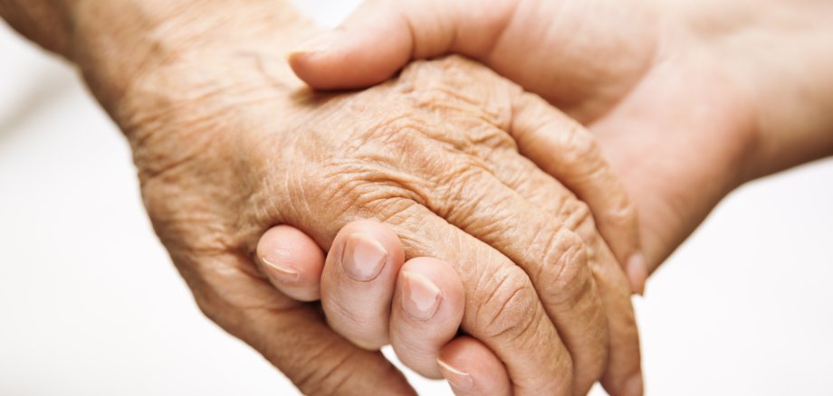 Haltende Hände eines Senioren und eines Erwachsenen