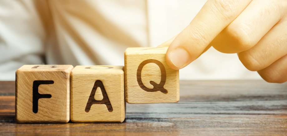 Businessman puts wooden blocks with the word FAQ (frequently asked questions). Collection of frequently asked questions on any topic and answers to them. Instructions and rules on Internet sites